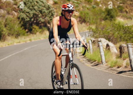 Junge Frau Triathlon-Sportler Radfahren. Kaukasische Sportlerin Reiten auf Landstraße. Stockfoto