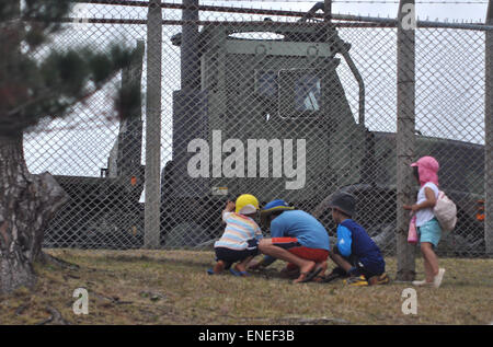 Okinawa, Japan: Kinder spielen durch den Zaun der amerikanischen Militärbasis Camp Schwab in Henoko Stockfoto