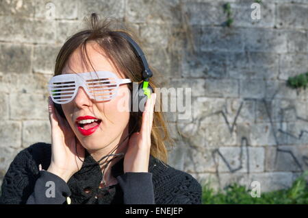 Glücklich verrücktes Mädchen Musikhören mit großen Sonnenbrille Stockfoto