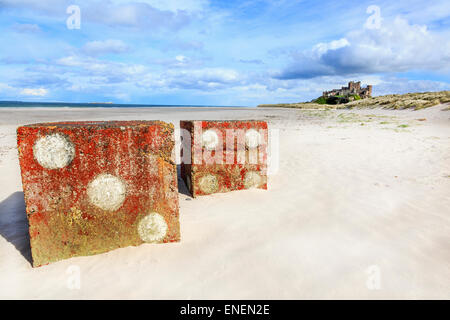 Zwei 2. Weltkrieg anti-Tank Betonblöcke, malte als Würfel, am Strand von Bamburgh mit Bamburgh Castle, Northumberland, En Stockfoto