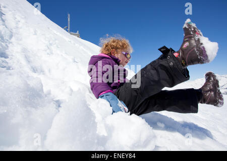 Junges Mädchen rutscht Schnee Damm Stockfoto