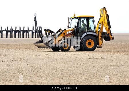 Gelbe JCB Lytham St Annes mit am Strand Teil des alten Pier Struktur und Meer im Hintergrund Stockfoto