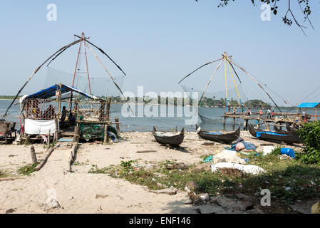 Eine Reihe von Fischerbooten und Netzen neben einem der chinesischen Fischernetze in Fort Cochin in Kochi, Kerala, Indien. Stockfoto