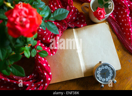 Altes Buch öffnen und Rosen auf hölzernen Hintergrund Stockfoto