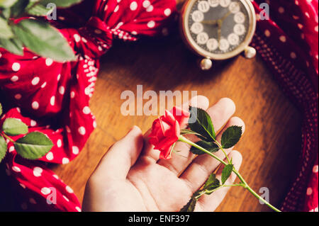 Hand mit schönen rosa Rose auf hölzernen Retro-Hintergrund. Stockfoto