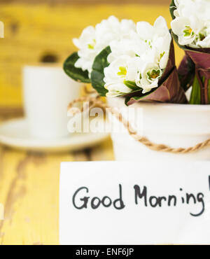 Tasse schwarzen Kaffee und ersten Schneeglöckchen Frühlingsblumen auf dem alten Tisch Stockfoto