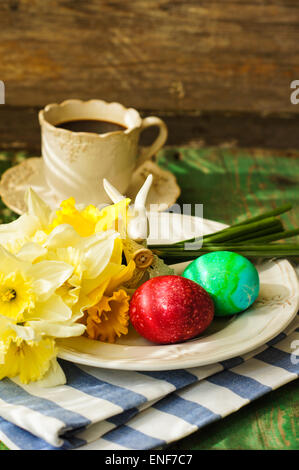 Frühling festlichen Ostern Esstisch Rahmen mit gelben Narzissen Blumen, Servietten und Vintage Besteck auf einem Holzbrett Stockfoto
