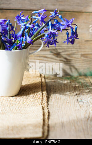 Blaue Hyazinthen in der Vase auf dem Holztisch auf Sackleinen Serviette Stockfoto