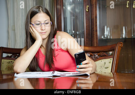 Junges Mädchen lernen und SMS auf einem Mobiltelefon. Stockfoto