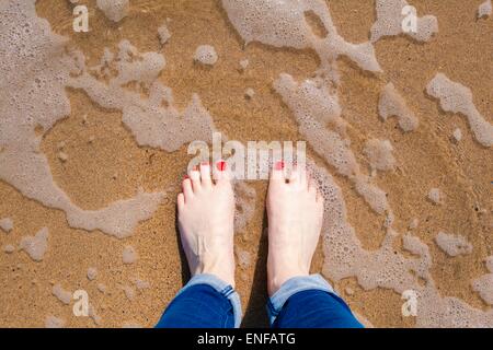 Blick auf Füßen stehend im Wasser am Strand Stockfoto