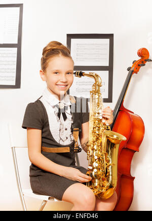 Glückliches Mädchen in der Schule verkleiden mit Alt-Saxophon Stockfoto