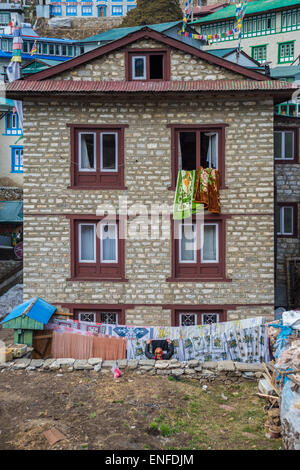 Eine nepalesische Frau Aufhängen von Wäsche auf der Wäscheleine, vor ihrem Haus in Namche Bazar Stockfoto