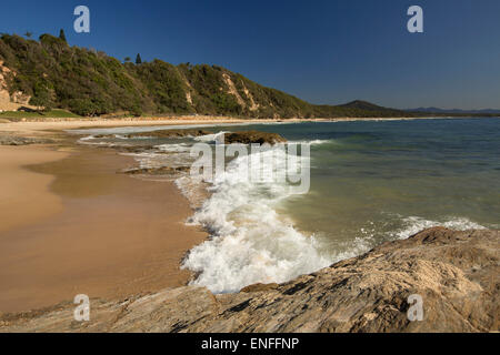 Sandstrand in geschützten Bucht mit blauem Wasser und niedrige weiße angeschnittene Ärmel Wellen des Pazifischen Ozeans Plätschern ans Ufer Nambucca Heads NSW Australia Stockfoto