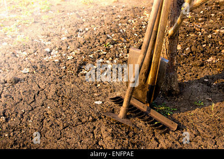 Alten Retro-Gartengeräte (Schaufel, Rechen, Grubber) über braune Erde (gepflügte Land) großaufnahme, horizontale.  Landwirtschaft, Gartenbau, Stockfoto