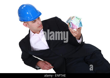 Unternehmer, die auf dem Boden liegend mit einem Haus-förmigen Box in der hand Stockfoto