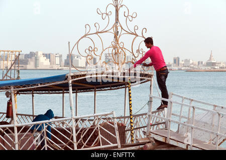 Arbeiter auf einer Dhau Touristenboot bereiten ihre angedockten Schiffe für den Abflug in Doha, Katar. Stockfoto