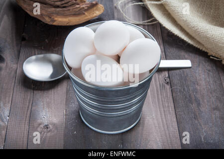 Eiern in einem Eimer auf einem schwarzen Holztisch Stockfoto