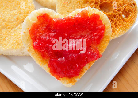 Nahaufnahme einer Platte mit herzförmigen Toast und Erdbeermarmelade Stockfoto