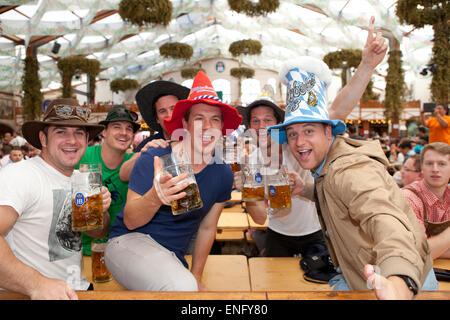 Besucher sitzen im Zelt auf dem Oktoberfest und Bier in einen Bierkrug Stockfoto