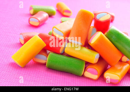 Nahaufnahme von einem Haufen von Lakritz-Bonbons in verschiedenen Farben auf einem rosa Hintergrund Stockfoto