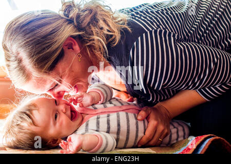 Lächelndes kaukasischen Mutter wiegt Babymädchen Stockfoto