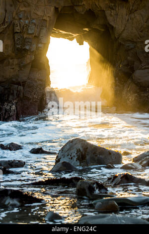 Sunbeam durchschimmern Felsformation zu Wellen des Ozeans Stockfoto