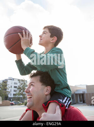 Kaukasische Vater Sohn mit Basketball auf den Schultern tragen Stockfoto