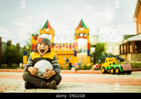 Kaukasische junge mit Mund offen halten Ball am Spielplatz Stockfoto