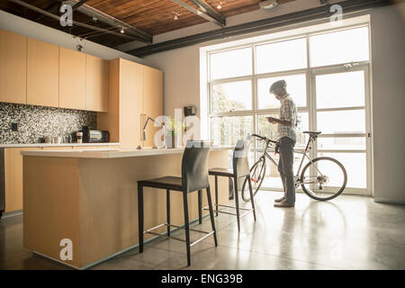 Schwarze Geschäftsmann mit dem Fahrrad mit Handy im Büro Küche Stockfoto