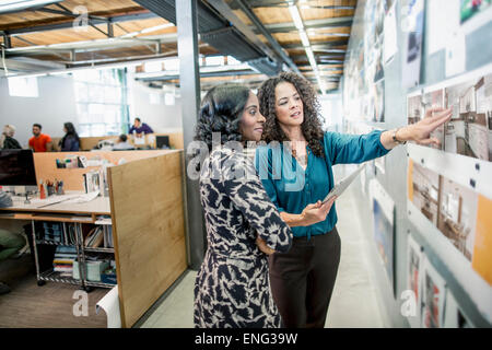 Geschäftsfrauen Prüfung Fotografien an der Wand im Büro Stockfoto