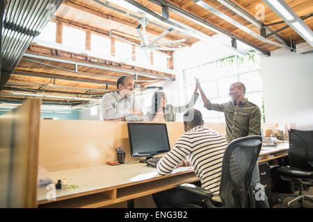Geschäftsleute, die am Schreibtisch im Büro feiern Stockfoto
