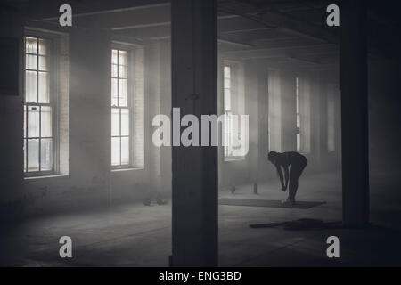 Schwarze Frau, die Dehnung in dunklen Turnhalle Stockfoto
