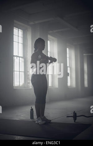 Schwarze Frau Heben von Gewichten in dunklen Turnhalle Stockfoto