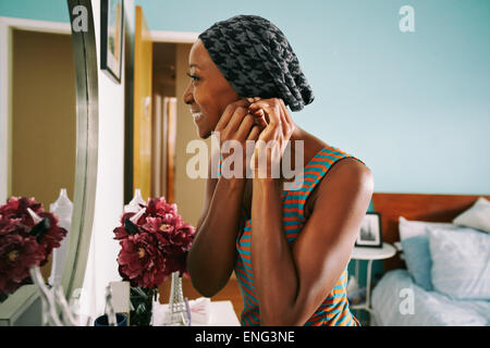 Lächelnde afroamerikanische Frau Ohrring anbringen Stockfoto