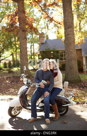 Paar sitzt auf Roller im Vorort Stockfoto