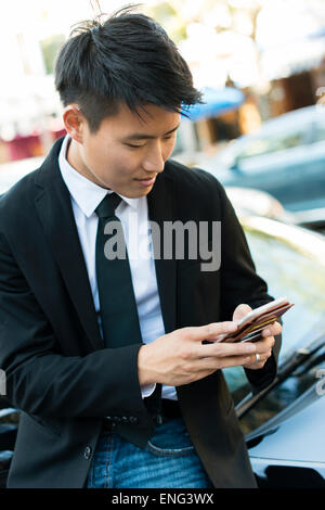 Koreanischer Geschäftsmann mit Handy in der Nähe von Auto Stockfoto