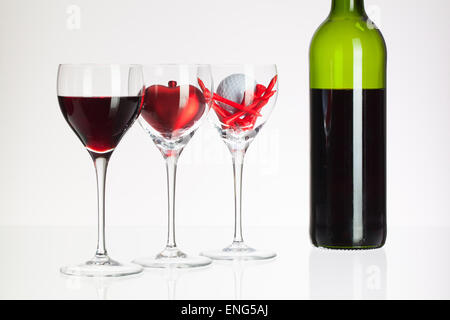 Weingläser mit roten Wein, Herz und Golf Ball auf weißen Tisch Stockfoto