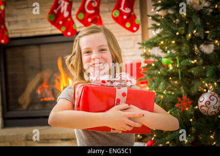 Kaukasische Mädchen umarmt Weihnachtsgeschenk Stockfoto