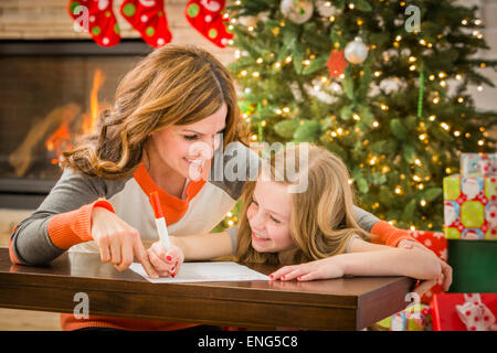 Kaukasische Mutter und Tochter zu Weihnachten an den Weihnachtsmann schreiben Stockfoto