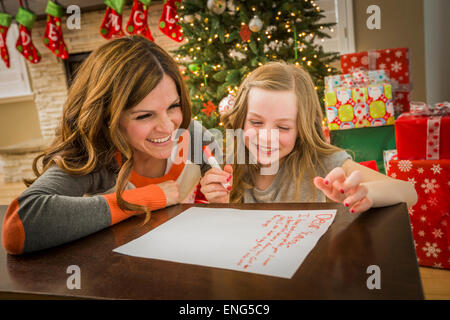 Kaukasische Mutter und Tochter zu Weihnachten an den Weihnachtsmann schreiben Stockfoto