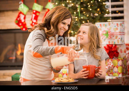 Kaukasische Mutter und Tochter verlassen Kekse und Milch für den Weihnachtsmann zu Weihnachten Stockfoto