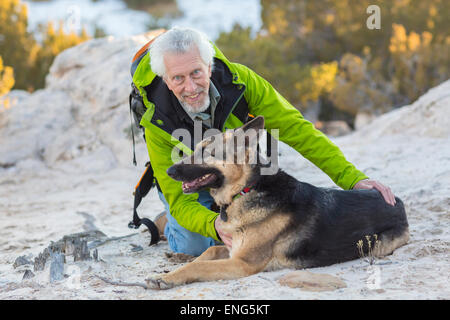 Ältere Mann Petting Hund auf felsigen Hügel Stockfoto