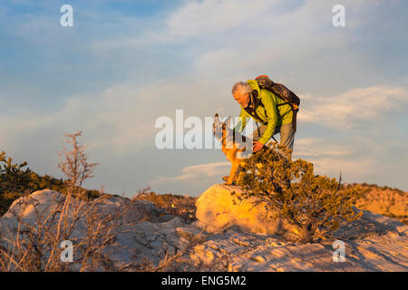 Älterer Mann und Hund auf abgelegenen Felsformationen Stockfoto