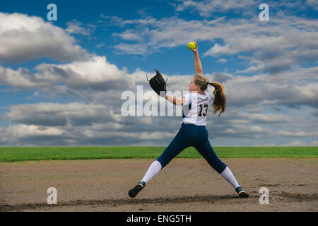 Kaukasische Softball Spieler pitching Ball im Feld Stockfoto