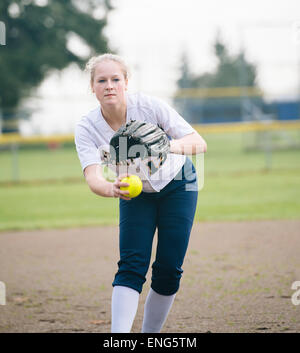 Kaukasische Softball Spieler pitching Ball im Feld Stockfoto