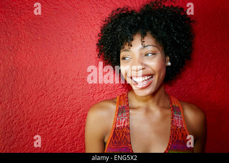 Lächelnde schwarze Frau stand in der Nähe rote Wand Stockfoto