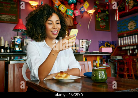 Gemischte Rassen Frau mit Handy im café Stockfoto