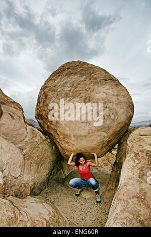 Hispanic Frau heben Boulder auf felsigen Hügel Stockfoto