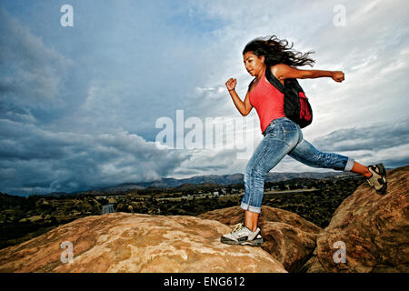 Hispanic Frau springen Gletscherspalte auf Felsformation Stockfoto