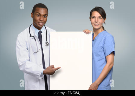 Multiethnische Ärzteteam ein afrikanischer Arzt in einem Kittel und Stethoskop und einer Krankenschwester in Peelings mit einem leeren weißen Schild Stockfoto